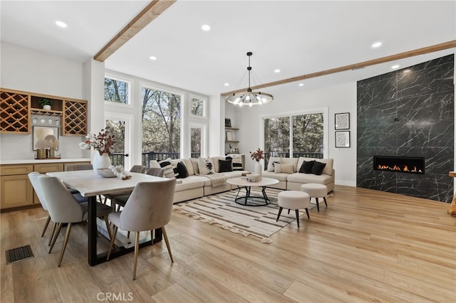 dining room with light wood finished floors, a premium fireplace, a wealth of natural light, and recessed lighting