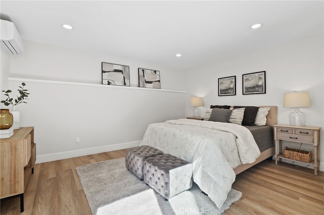 bedroom featuring an AC wall unit, recessed lighting, light wood-style flooring, and baseboards