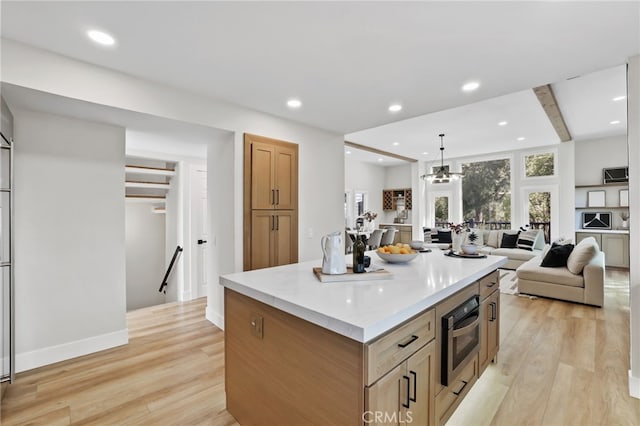 kitchen with open floor plan, a center island, light countertops, light wood-type flooring, and recessed lighting