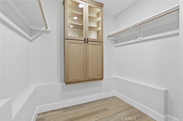 walk in closet with light wood-style flooring