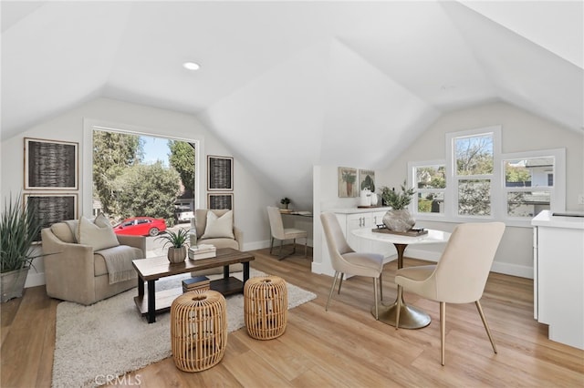 living area featuring lofted ceiling, plenty of natural light, and light wood-style floors