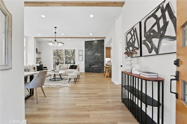 entrance foyer featuring recessed lighting, a notable chandelier, a fireplace, and light wood-style flooring