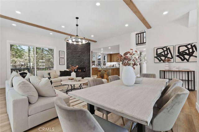 dining area featuring a high end fireplace, light wood-type flooring, beam ceiling, and recessed lighting