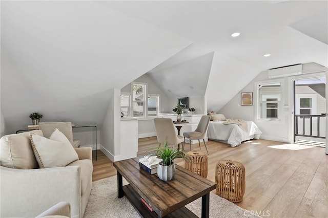 interior space featuring lofted ceiling, baseboards, access to outside, light wood-type flooring, and a wall mounted air conditioner