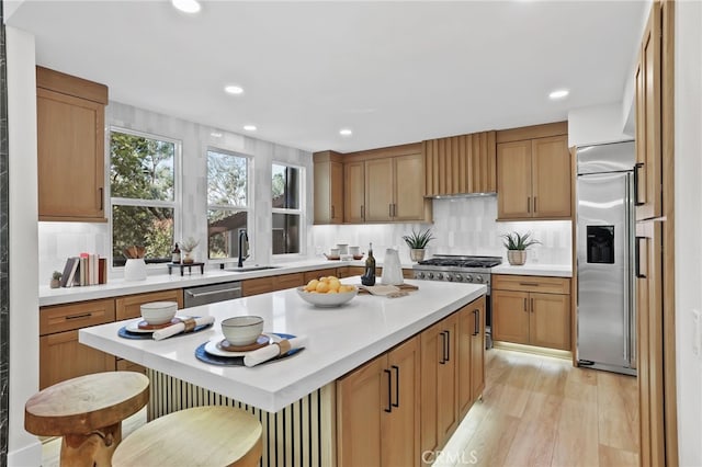 kitchen featuring premium appliances, a sink, light countertops, custom exhaust hood, and a center island