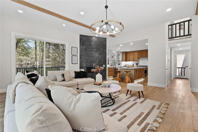 living area featuring light wood-style floors, recessed lighting, baseboards, and an inviting chandelier