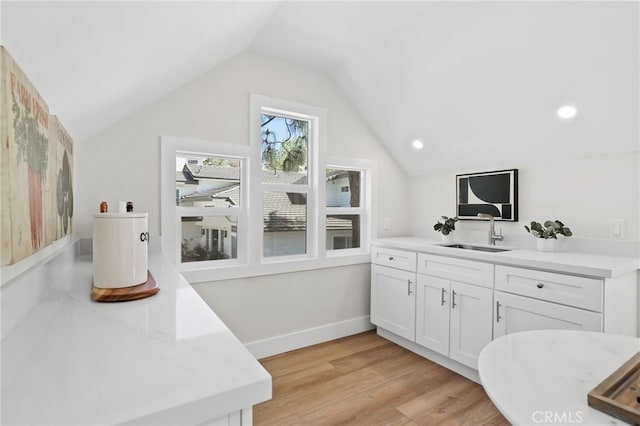 interior space featuring lofted ceiling, vanity, baseboards, and wood finished floors