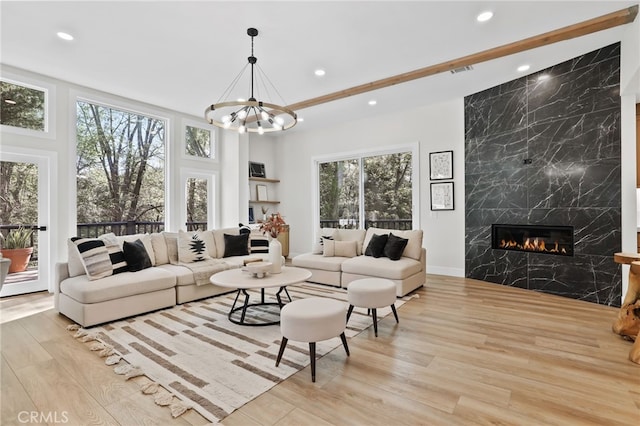 living room with light wood finished floors, a premium fireplace, an inviting chandelier, and recessed lighting