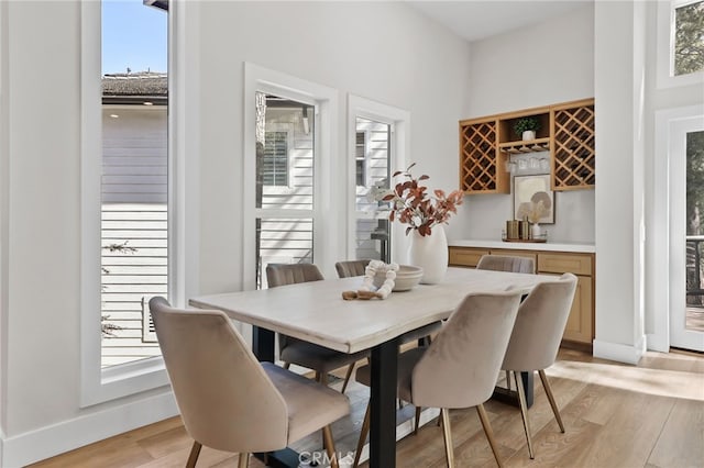 dining room featuring light wood-type flooring, baseboards, and bar area