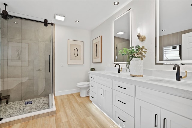 full bathroom with wood finished floors, a sink, toilet, and a shower stall