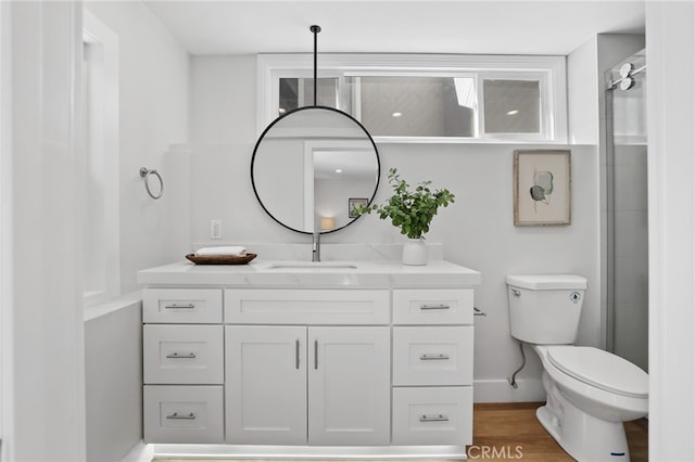 bathroom featuring baseboards, vanity, toilet, and wood finished floors