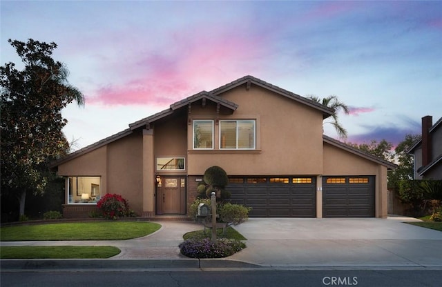 view of front of house featuring stucco siding, driveway, an attached garage, and a front yard