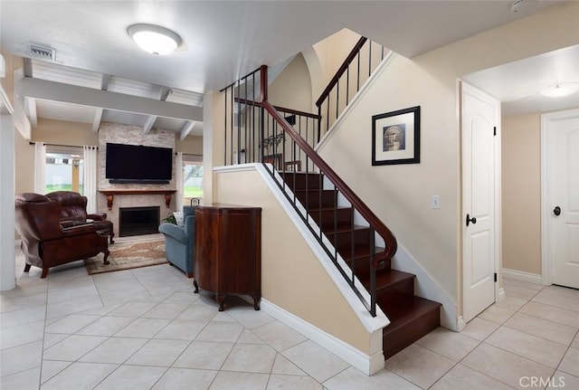 stairway with a large fireplace, beamed ceiling, tile patterned flooring, and baseboards