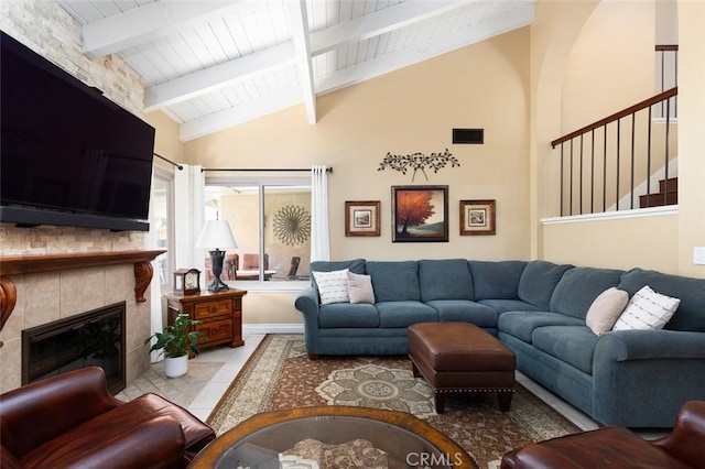 tiled living area with visible vents, a tile fireplace, lofted ceiling with beams, wooden ceiling, and stairs