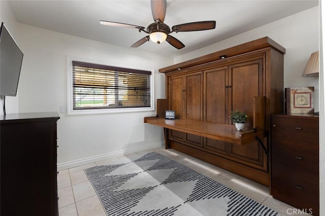 interior space with a ceiling fan, baseboards, and light tile patterned floors