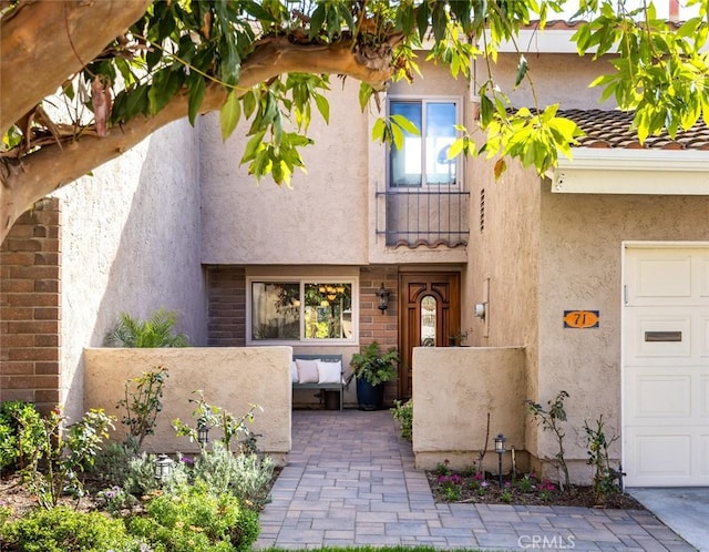 view of front of property featuring an attached garage, a tile roof, and stucco siding