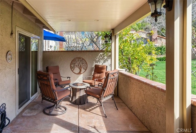 view of patio with an outdoor fire pit and a balcony