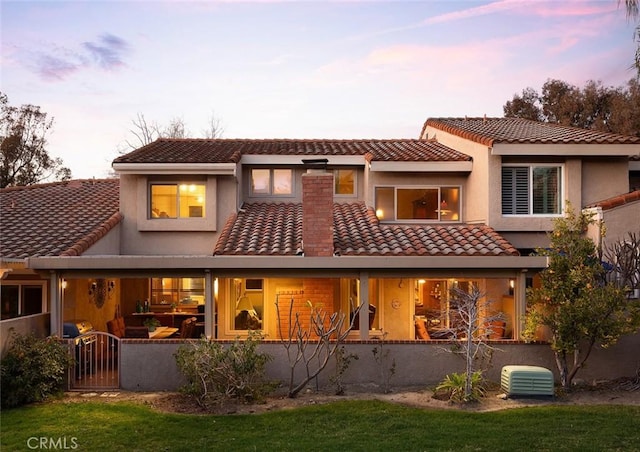 rear view of house with a tile roof, a gate, and stucco siding