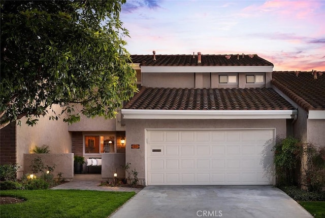 multi unit property featuring a garage, driveway, a tiled roof, and stucco siding