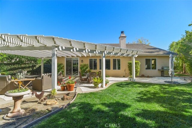 back of house featuring a chimney, a patio, a lawn, and stucco siding