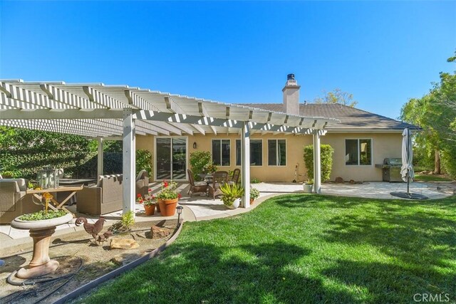 back of house with a chimney, stucco siding, a lawn, a patio area, and a pergola
