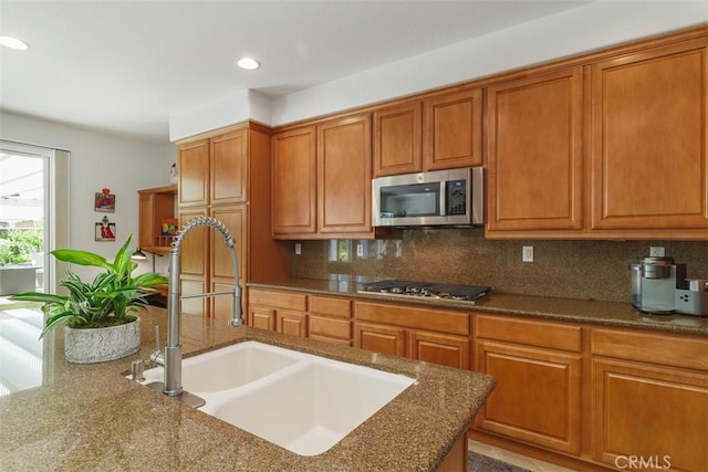 kitchen featuring tasteful backsplash, brown cabinets, stainless steel appliances, and a sink