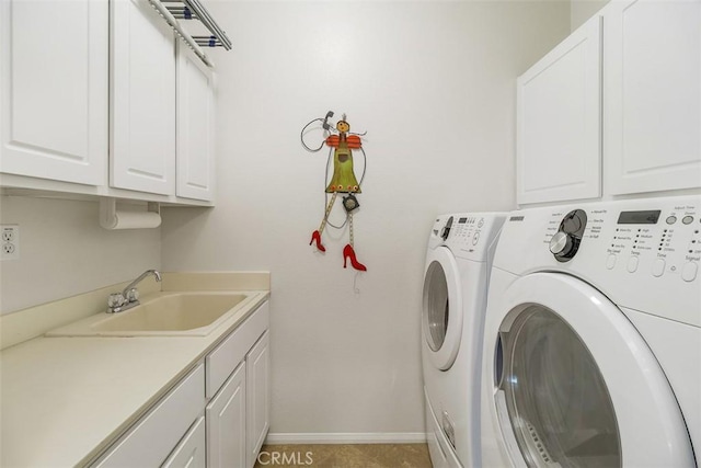 laundry area with cabinet space, a sink, washer and clothes dryer, and baseboards