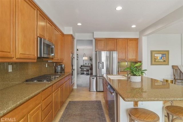 kitchen with recessed lighting, a breakfast bar, backsplash, stone countertops, and appliances with stainless steel finishes
