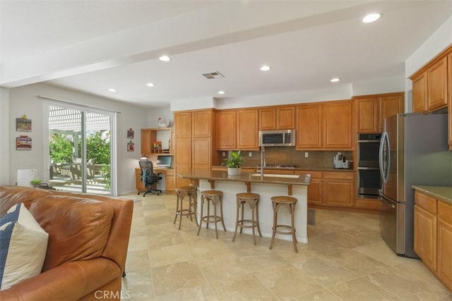 kitchen with decorative backsplash, stainless steel appliances, a kitchen bar, visible vents, and open floor plan