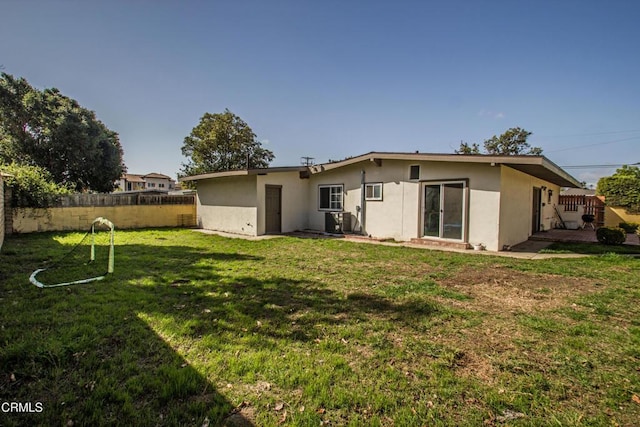 back of house featuring a yard, cooling unit, fence, and stucco siding