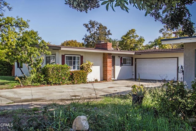 ranch-style home with brick siding, a chimney, stucco siding, a garage, and driveway