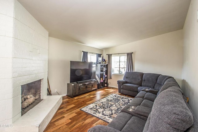 living room with a fireplace, baseboards, and wood finished floors