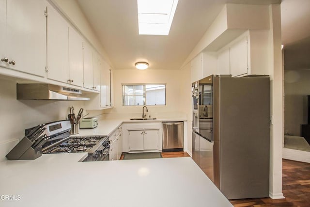 kitchen with appliances with stainless steel finishes, white cabinets, a sink, and under cabinet range hood