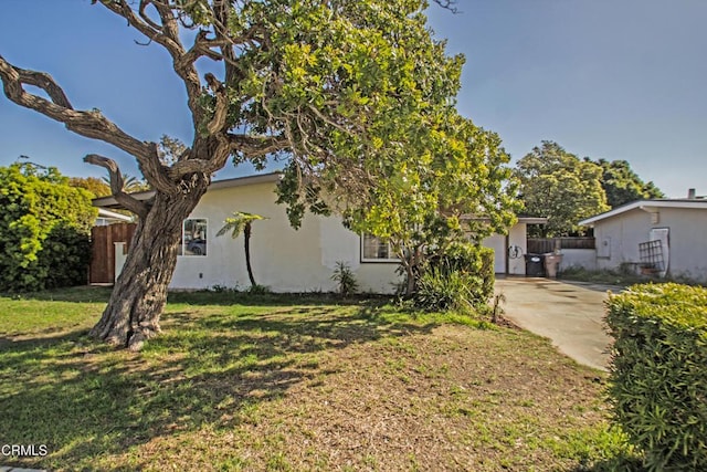 view of front of home with a garage, fence, driveway, stucco siding, and a front yard