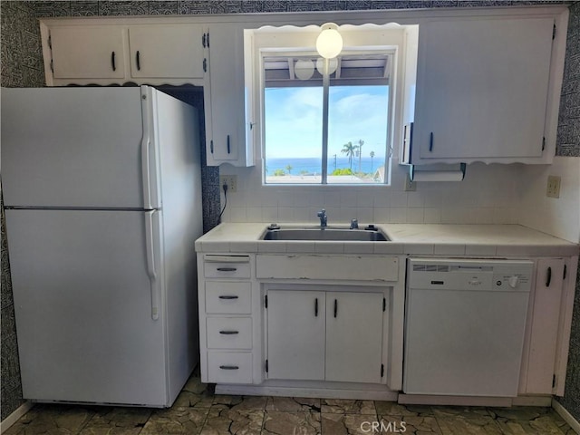 kitchen with tasteful backsplash, white appliances, white cabinetry, and a sink