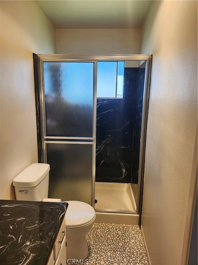 bathroom with vanity, tile patterned flooring, a shower stall, and toilet