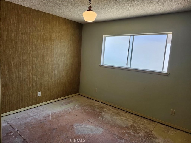 spare room with a textured ceiling and baseboards