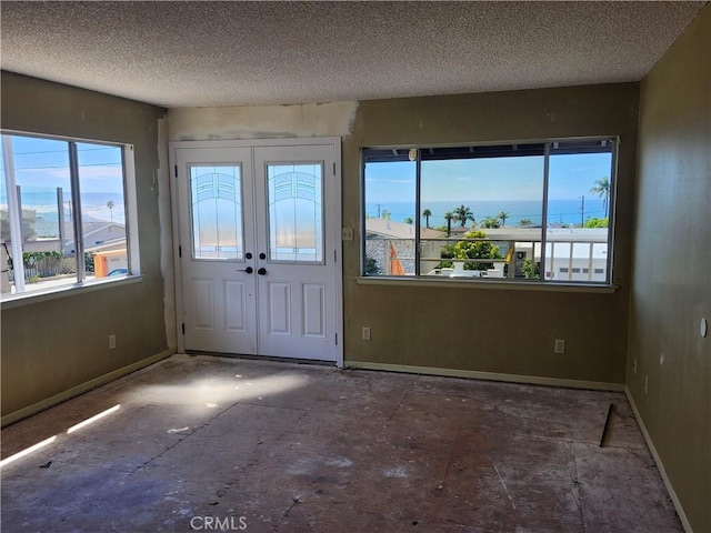 foyer featuring french doors, a textured ceiling, and baseboards