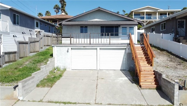 view of front of property featuring an attached garage, fence, stairs, concrete driveway, and stucco siding