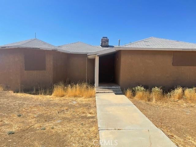 doorway to property featuring a chimney and stucco siding