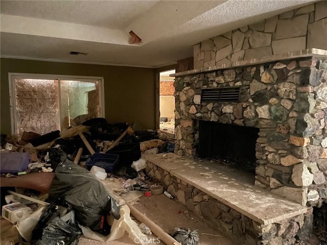 miscellaneous room featuring visible vents, a raised ceiling, a textured ceiling, and a stone fireplace