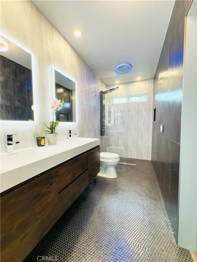 bathroom with tile walls, double vanity, tile patterned floors, toilet, and walk in shower