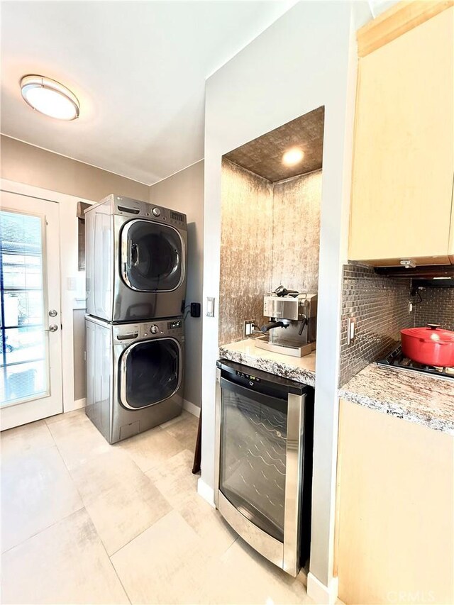 washroom featuring stacked washer / drying machine, baseboards, and wine cooler