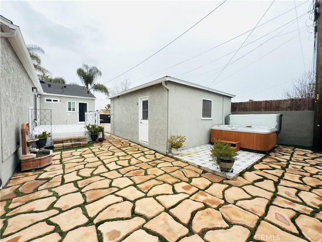 view of patio featuring an outdoor structure, fence, and a hot tub