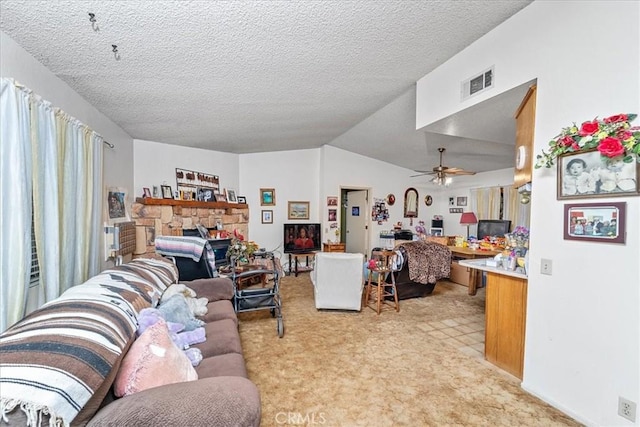 living area featuring a fireplace, visible vents, vaulted ceiling, a textured ceiling, and ceiling fan