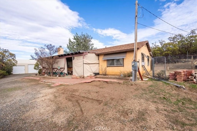 view of front of house featuring a chimney, fence, and stucco siding