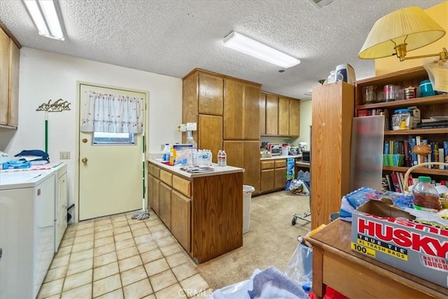 kitchen with brown cabinetry, a peninsula, light countertops, a textured ceiling, and washer and dryer