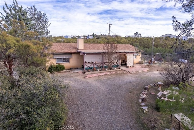 ranch-style home with a chimney and stucco siding