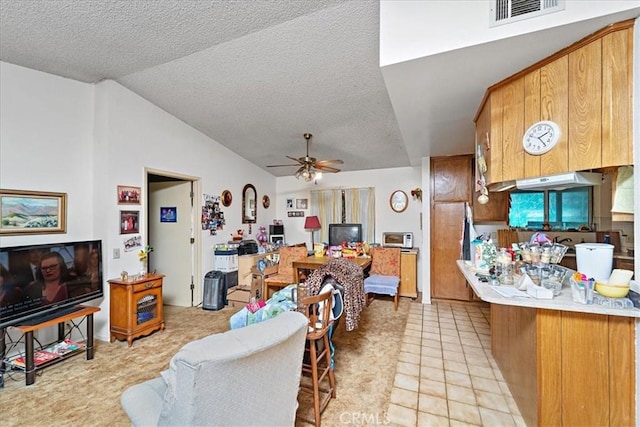 kitchen featuring brown cabinetry, light countertops, visible vents, and vaulted ceiling