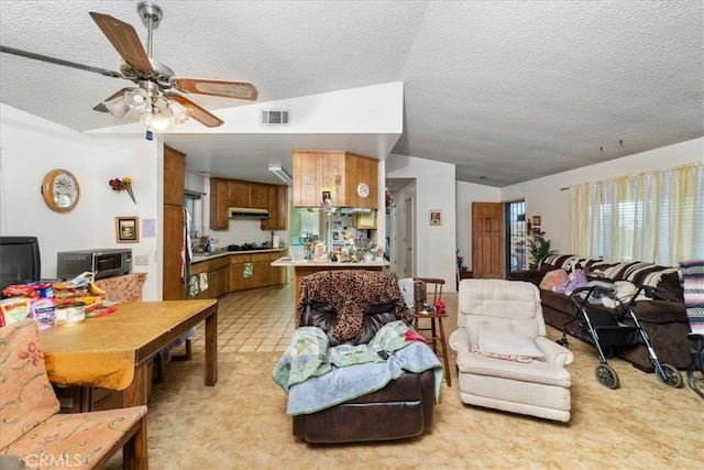 living area featuring visible vents, vaulted ceiling, a textured ceiling, and ceiling fan